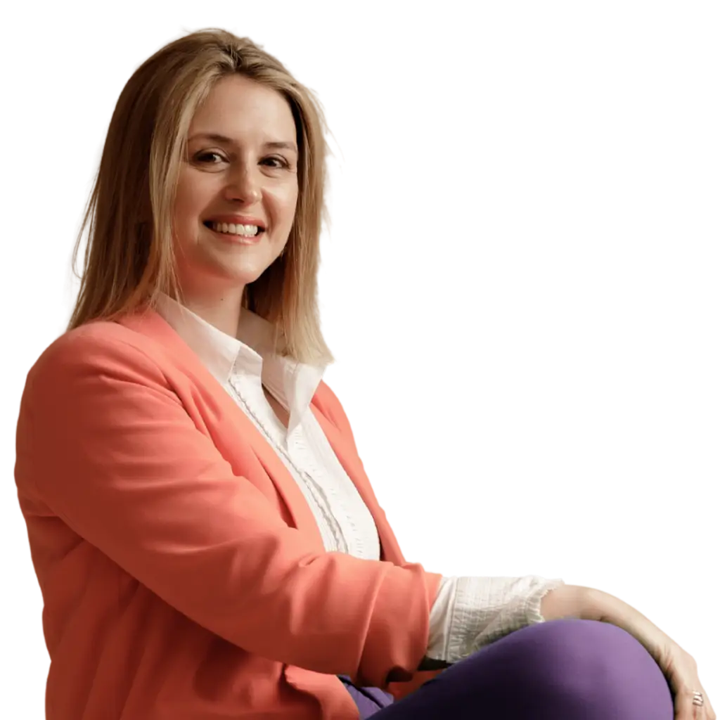 Andreia Rodrigues, psicóloga especialista em ansiedade, sentada e a sorrir com casaco coral.